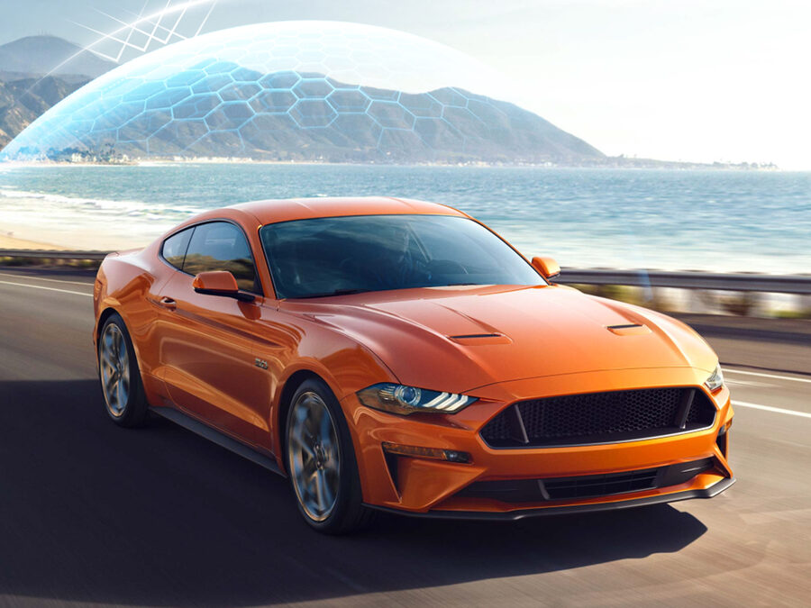 An orange sports car driving along a coastal road, showcasing VEPAGOO ceramic window tint film