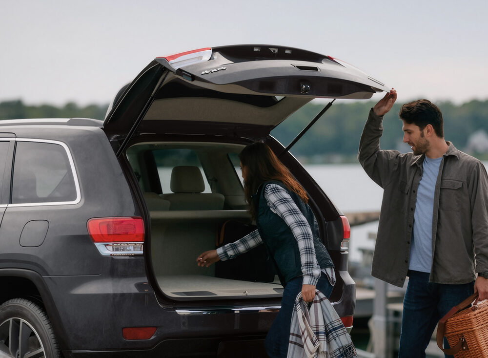 A couple loading a picnic basket into an SUV whose rear hatch is held open by VEPAGOO struts